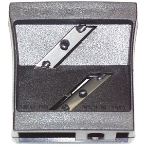 A double-blade pencil sharpener with a rectangular frame. The sharpener has two angled metal blades set within a black plastic casing designed to sharpen flat or carpenters pencils.
