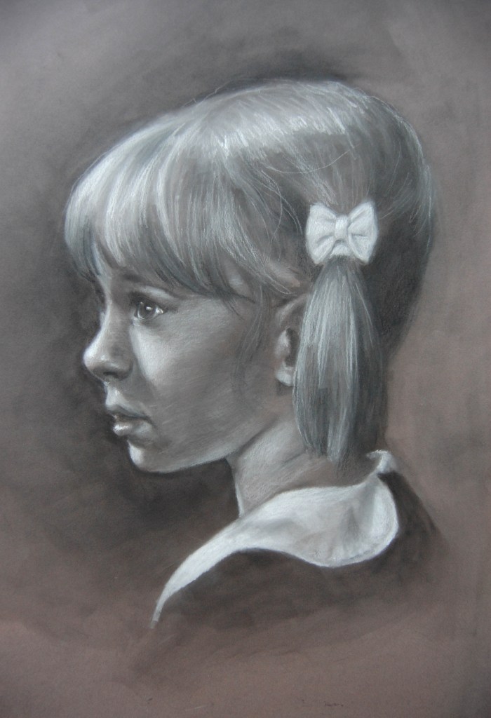 Portrait of a young girl drawn in charcoal. She has light-colored hair tied in a low side ponytail with a bow, and she wears a collared shirt. The girl is shown in profile looking to the left against a dark background. Artist Julia Maddalina.