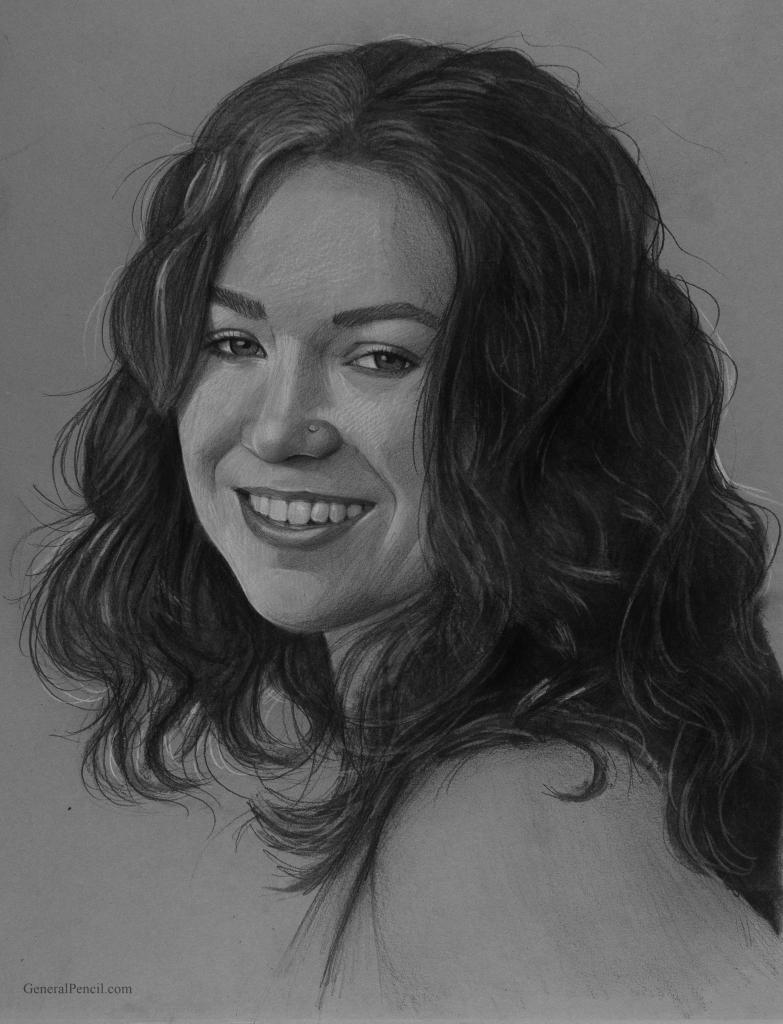 A black and white pencil sketch of a woman with wavy hair, smiling gently. The detailed drawing captures her facial features, including a nose ring. The background is plain, emphasizing her expression and hairstyle.
